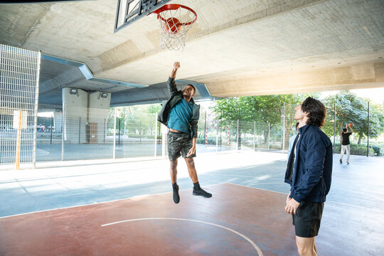 Young men playing basketball on an outdoor court underpass