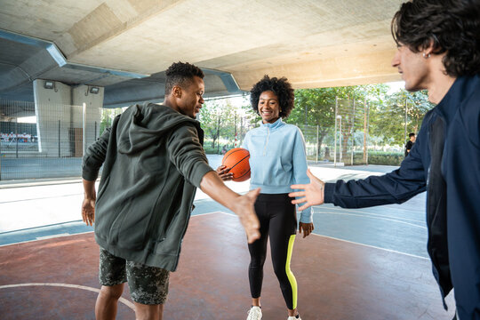 Friends playing basketball on urban court, greeting