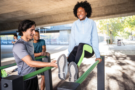 Friends training on parallel bar at outdoor fitness park