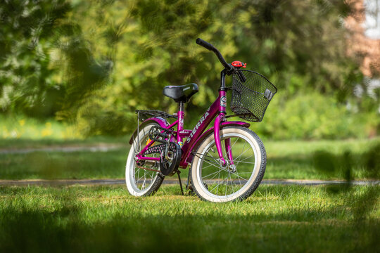Gothenburg, Sweden - May 05 2019: Small pink kids bicycle standing in sunny garden park.