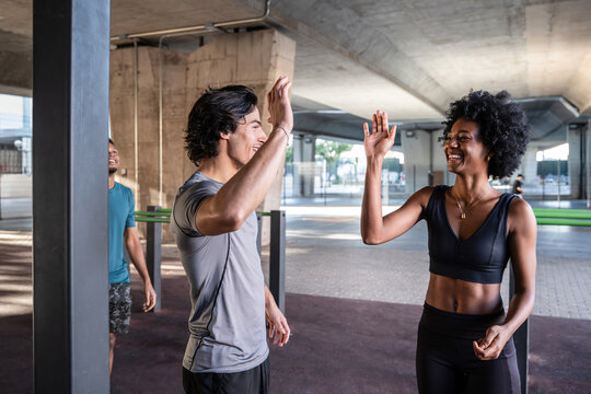 Friends high fiving after outdoor workout in urban gym