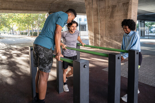 Friends training together on outdoor parallel bars in city