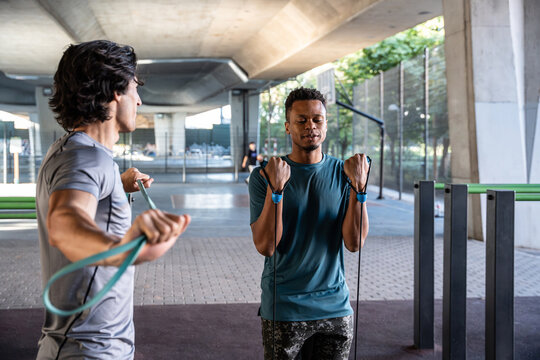 Men training with resistance band in urban gym outdoors