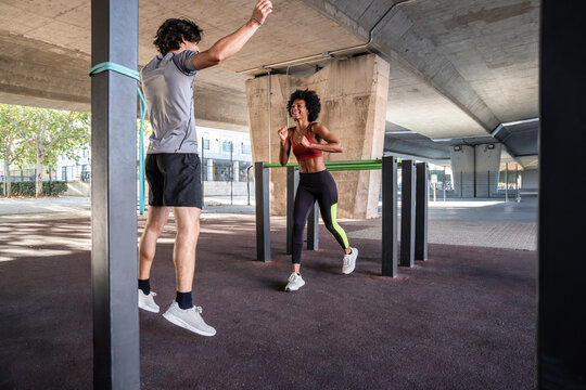 Outdoor partner workout with resistance band under bridge