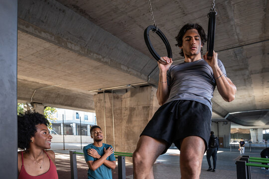 Athlete doing ring pull up at urban outdoor gym workout
