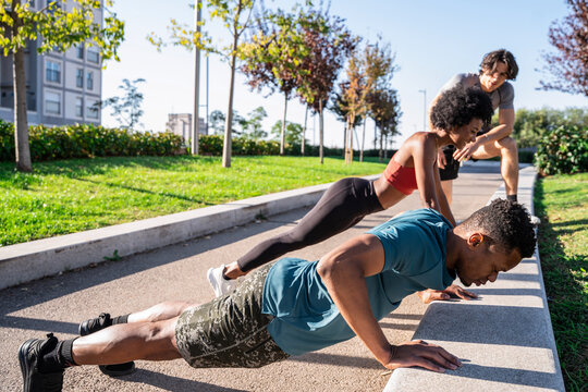 Outdoor group workout with friends doing push ups in park