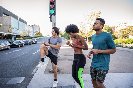 Urban runners warming up at crosswalk under traffic light