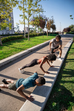 Outdoor workout with friends doing push up in city park