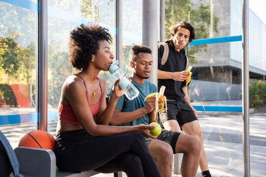 Fitness friends resting with banana and water after workout