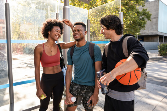 Friends with backpacks chatting after workout at bus stop