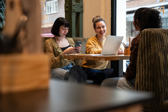 Multiethnic friends working and chatting in cozy cafe
