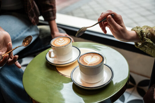 Multiethnic friends sharing latte at cafe table
