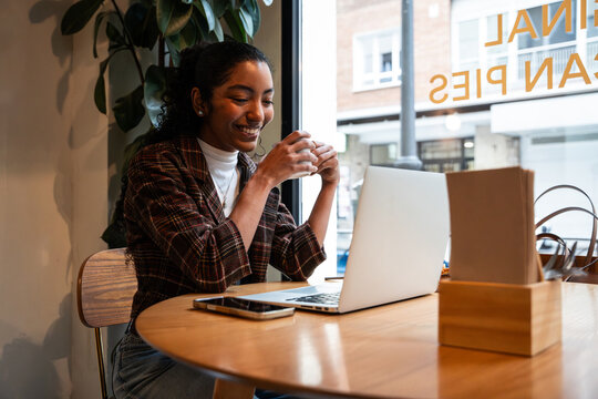 Young woman working on laptop in cafe with coffee break