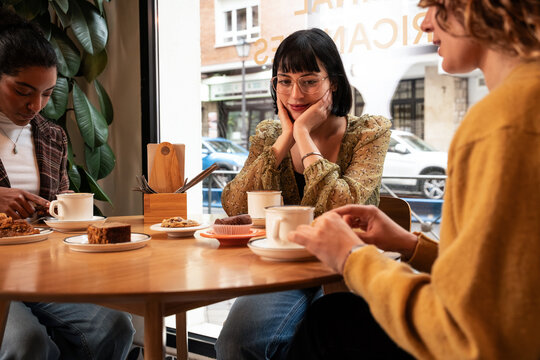 Multiethnic friends enjoying coffee and dessert in cafe