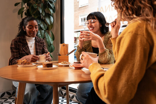 Multiethnic friend enjoy coffee and dessert in cafe
