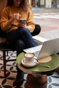 Remote work in cafe with laptop, phone, and coffee cup