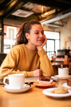 Woman relaxing in cafe with coffee and pastry indoors