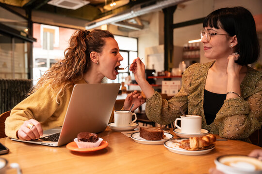 Two women sharing dessert while working in a cafe