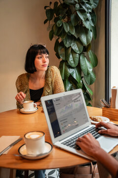 Casual cafe meeting with laptop, coffee, and quiet focus