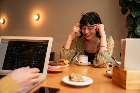 Smiling woman at cafe table with laptop and coffee cup