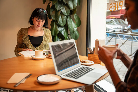 Multiethnic friends working on laptop in cozy cafe