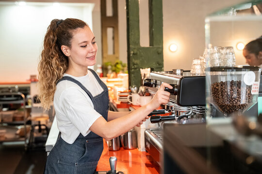 Barista preparing espresso with coffee grinder in cafe
