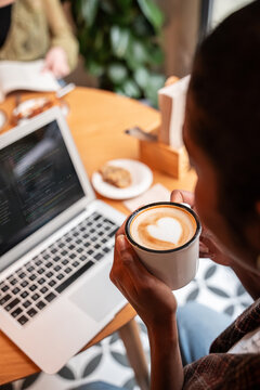 Remote work with coffee at laptop in cozy cafe setting