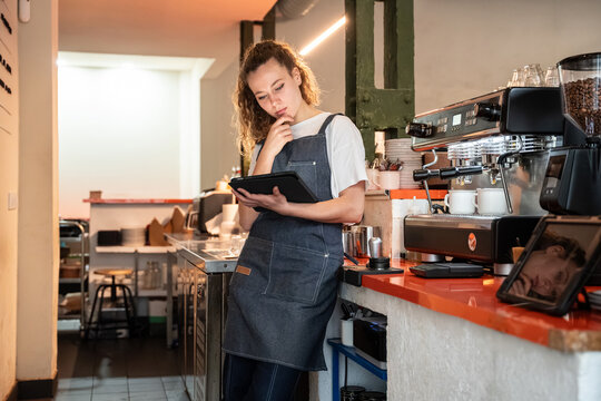 Barista checking inventory on tablet in modern coffee shop