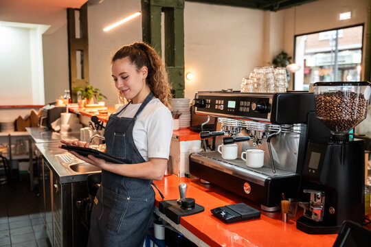 Barista using tablet at modern coffee shop espresso bar