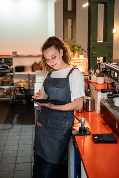 Barista using tablet beside espresso machine in cafe