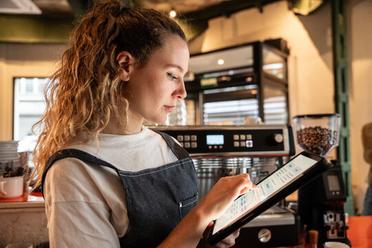 Barista using tablet for cafe orders behind coffee bar