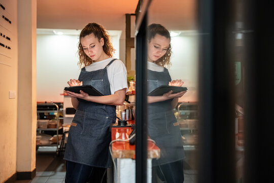 Young barista using tablet for cafe inventory management
