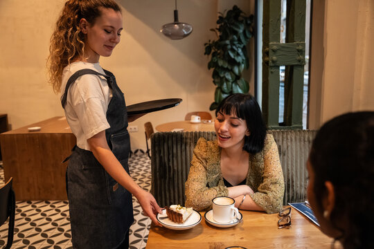 Multiethnic friends enjoying dessert served in cozy cafe