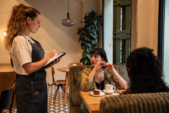 Waitress taking digital order from customer in cozy cafe