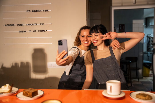 Two cafe workers take a selfie at brunch counter