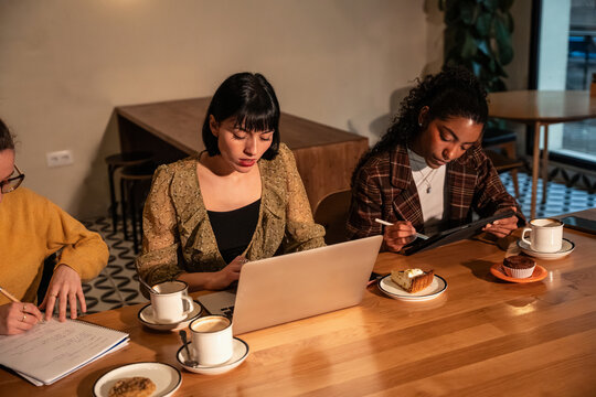Multiethnic colleagues working in cafe with laptop and tablet