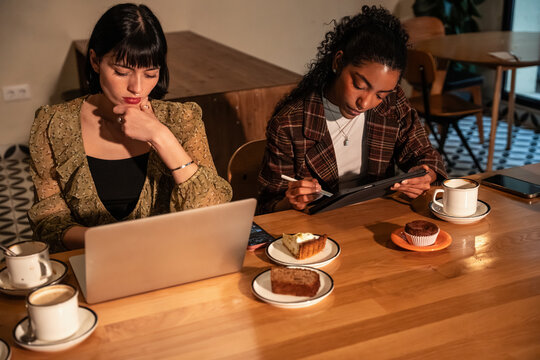 Multiethnic women working and studying in cafe together