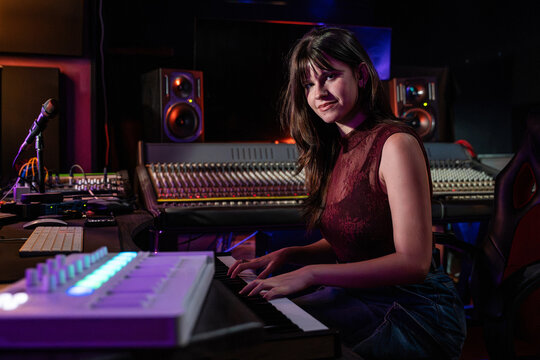Young musician playing keyboard in modern recording studio