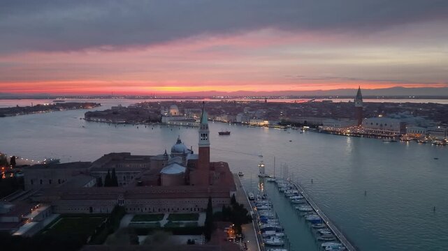 Venice aerial sunset over lagoon, boats gliding past basilica santa maria della salute, pastel sky casting. Italy