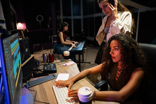 Women producing music in recording studio at night session