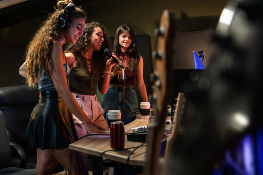 Young woman recording vocal and podcast audio in studio