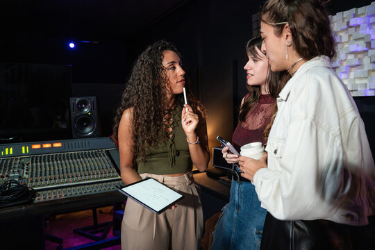 Women discuss audio production in recording studio control room