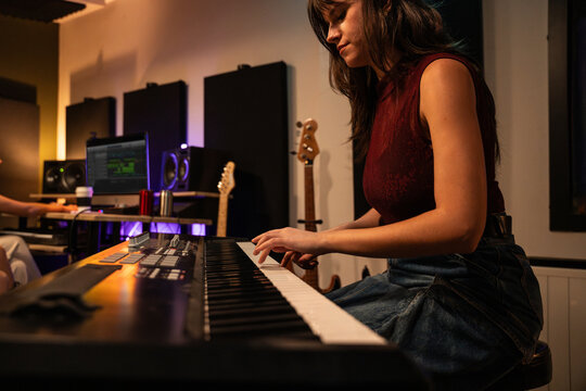 Music producer playing keyboard in home recording studio