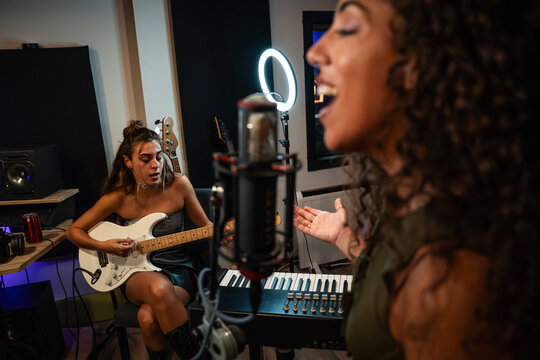 Female vocalist recording song with guitarist in studio