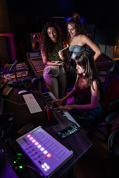 Women producing music in recording studio with keyboard