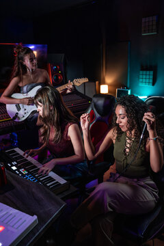 Women producing music in a studio with synth and guitar