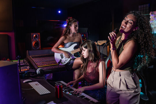 Female musicians recording vocals and guitar in studio