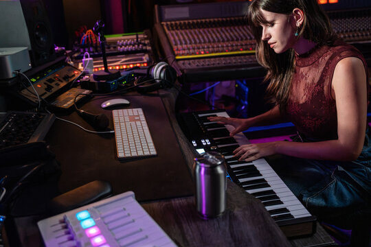 Music producer playing MIDI keyboard in studio at night