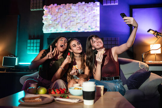 Women taking selfie in recording studio lounge with snacks