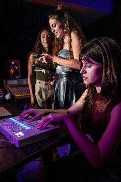 Women producing music in a recording studio at night